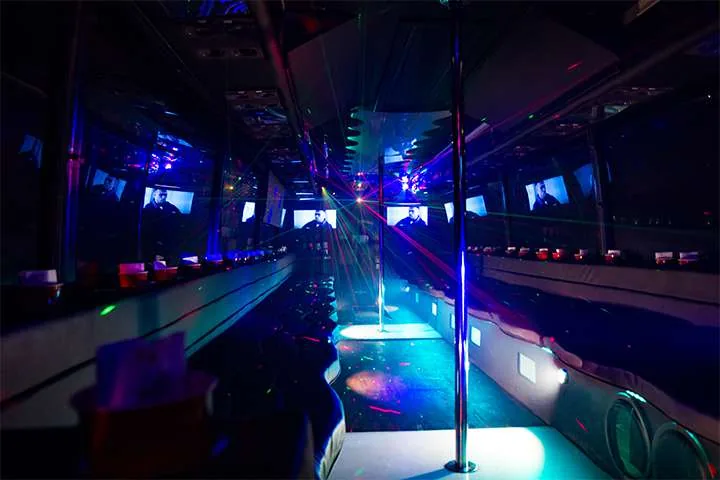 Inside a party bus with color-changing lights and a dance pole